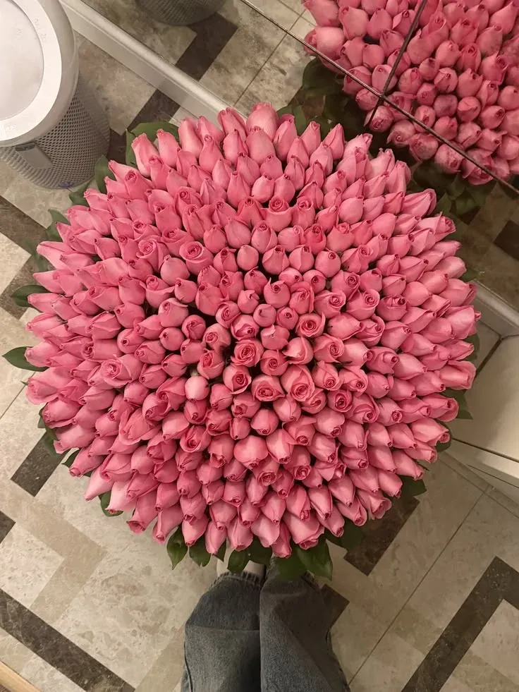 A round bouquet of pink roses photographed from above on a patterned tile floor
