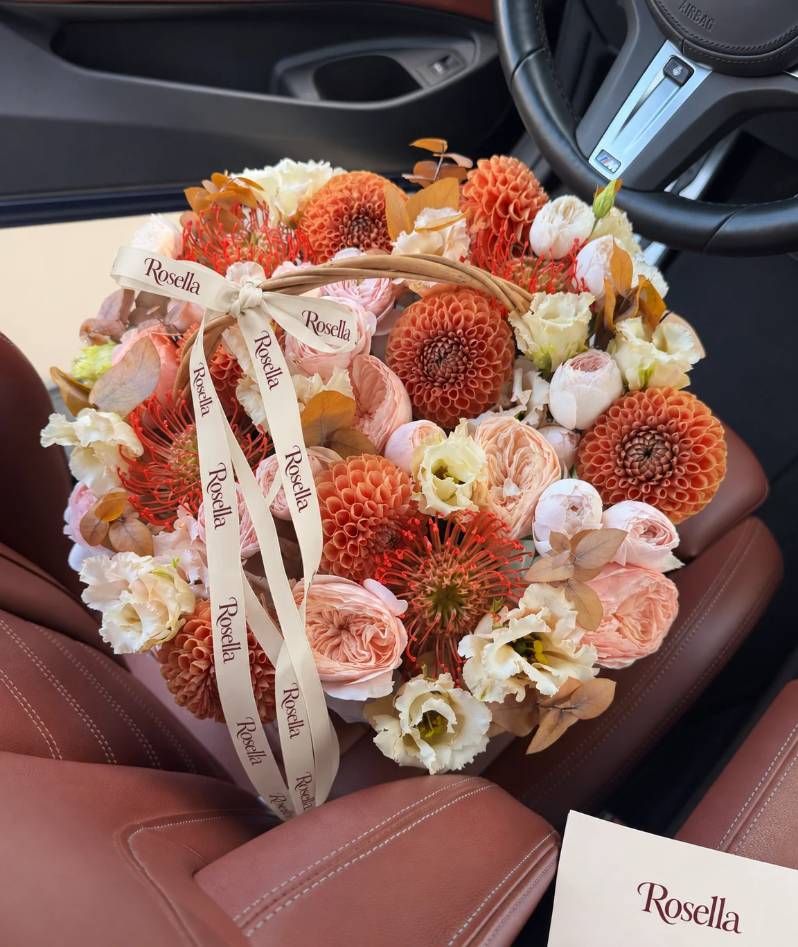 12 blush garden roses, 9 peach garden roses, 8 dahlias, 5 orange-red leucospermum (pincushion protea) & 22 lisianthus blooms in a basket