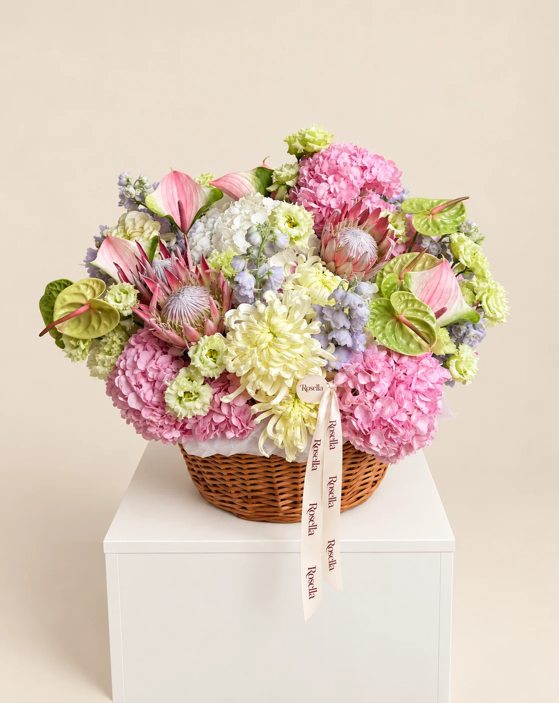 5 pink hydrangeas, 3 delphiniums, 5 chrysanthemums, 19 lisianthus blooms, 3 pink king protea, 5 green anthuriums, 1 white hydrangea & 4 pink anthuriums in a basket