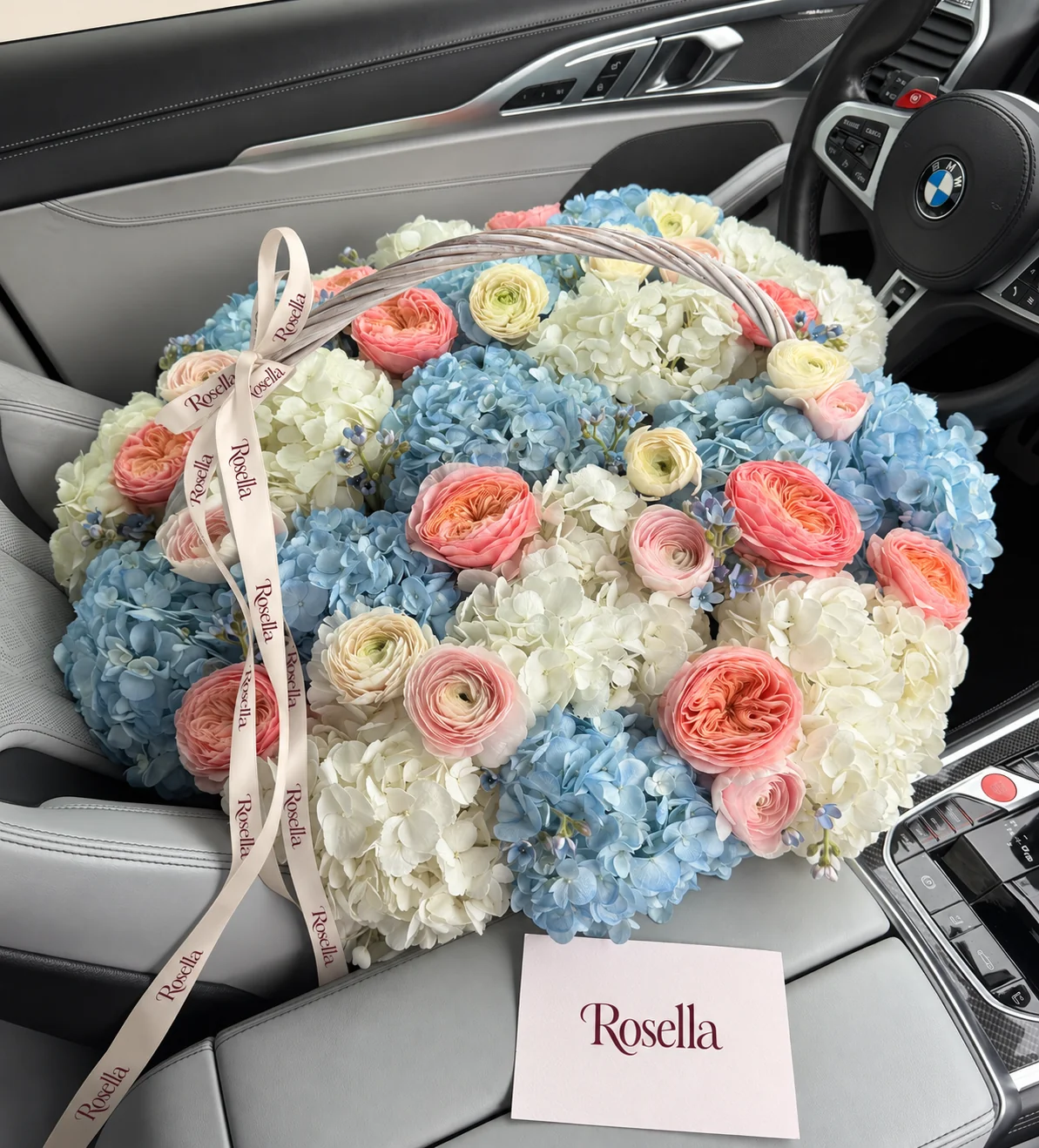 11 blue hydrangeas, 10 white hydrangeas, 13 garden roses, 7 cream ranunculus, 40 tweedia blooms, 6 blush ranunculus & 1 rose in a basket