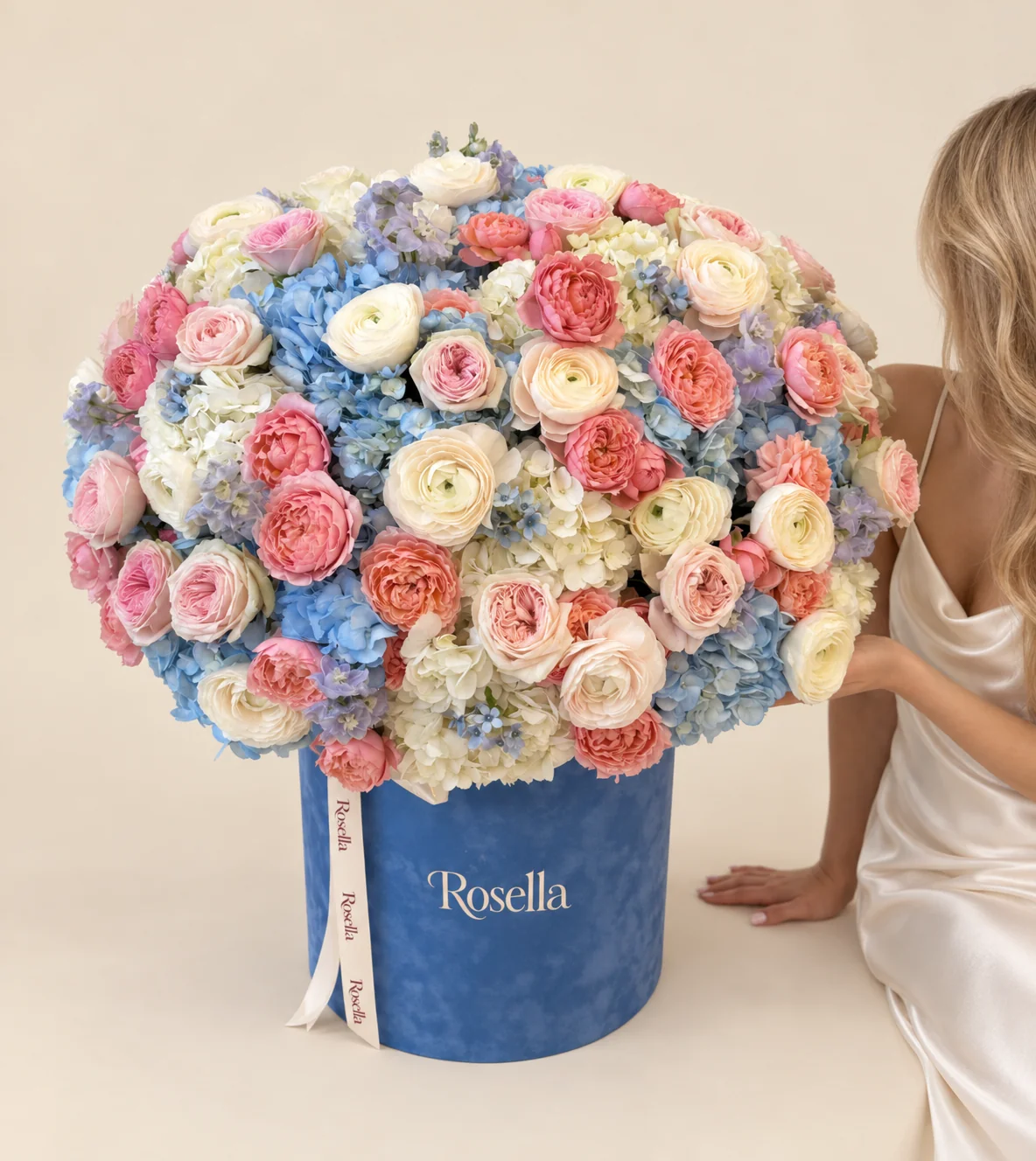 13 blue hydrangeas, 12 white hydrangeas, 16 ranunculus, 19 blush spray roses, 18 coral spray roses, 3 delphiniums, 10 peach spray roses & 27 tweedia blooms in a round box