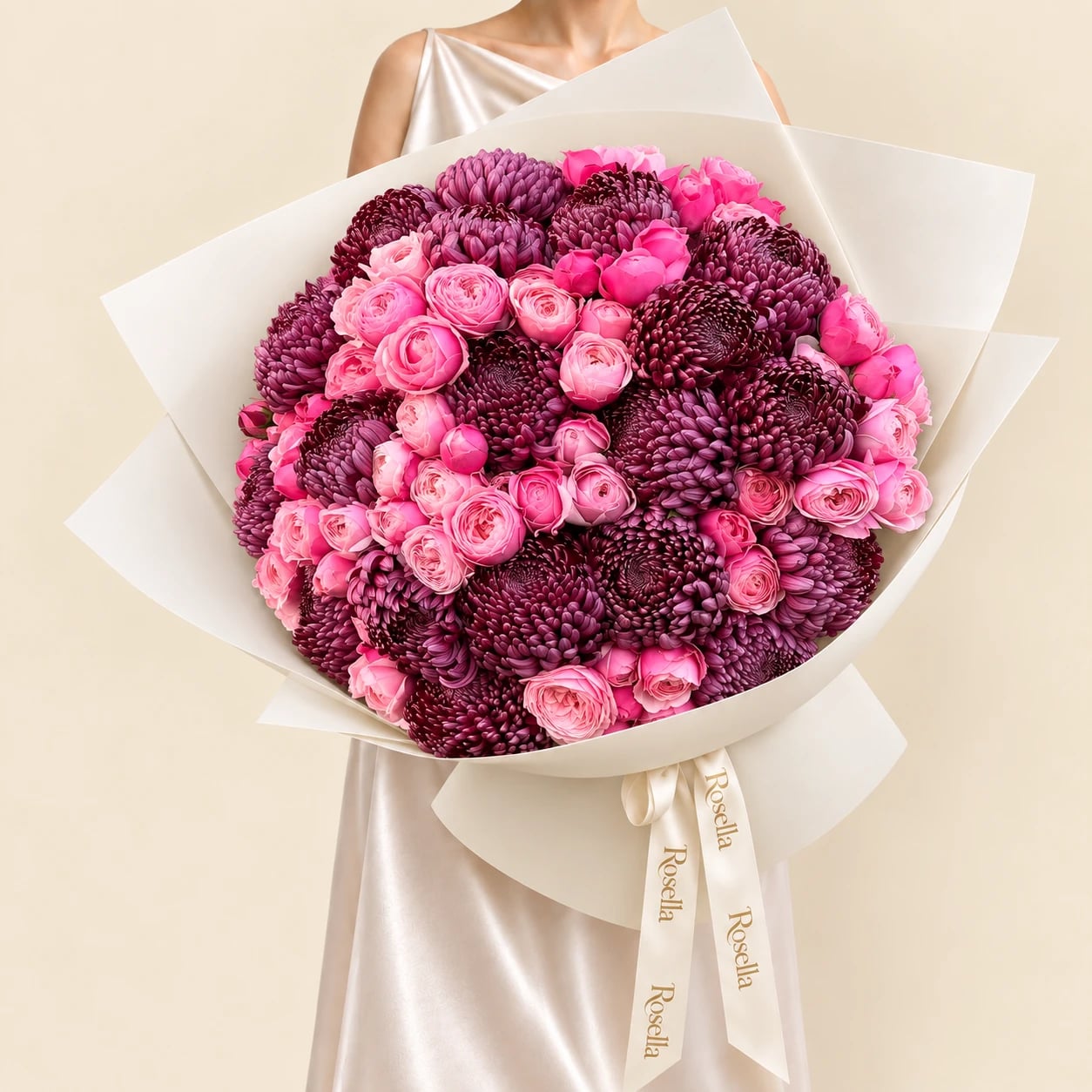 A huge dome of 20 deep plum Ganache chrysanthemums and 40 pink spray roses in wide ivory wrap tied with a Rosella ribbon, held by a woman in a champagne satin dress