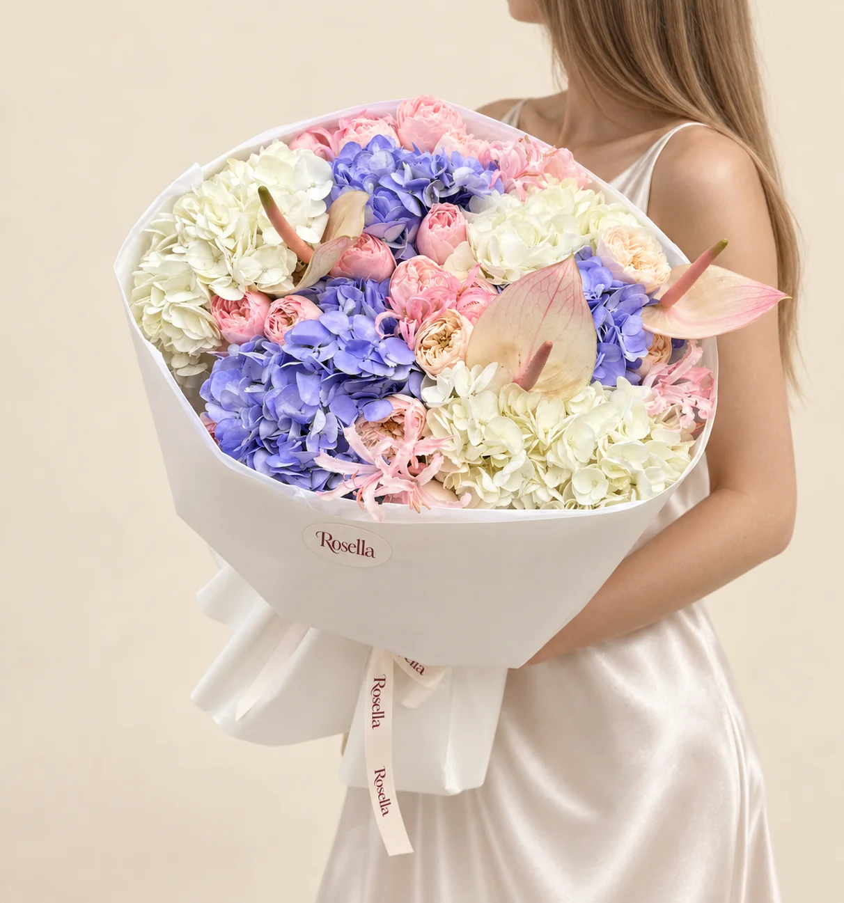 13 pink garden roses, 4 blue hydrangeas, 3 ivory hydrangeas, 4 cream garden roses, 12 pale pink nerine & 3 anthuriums in a hand-tied bouquet