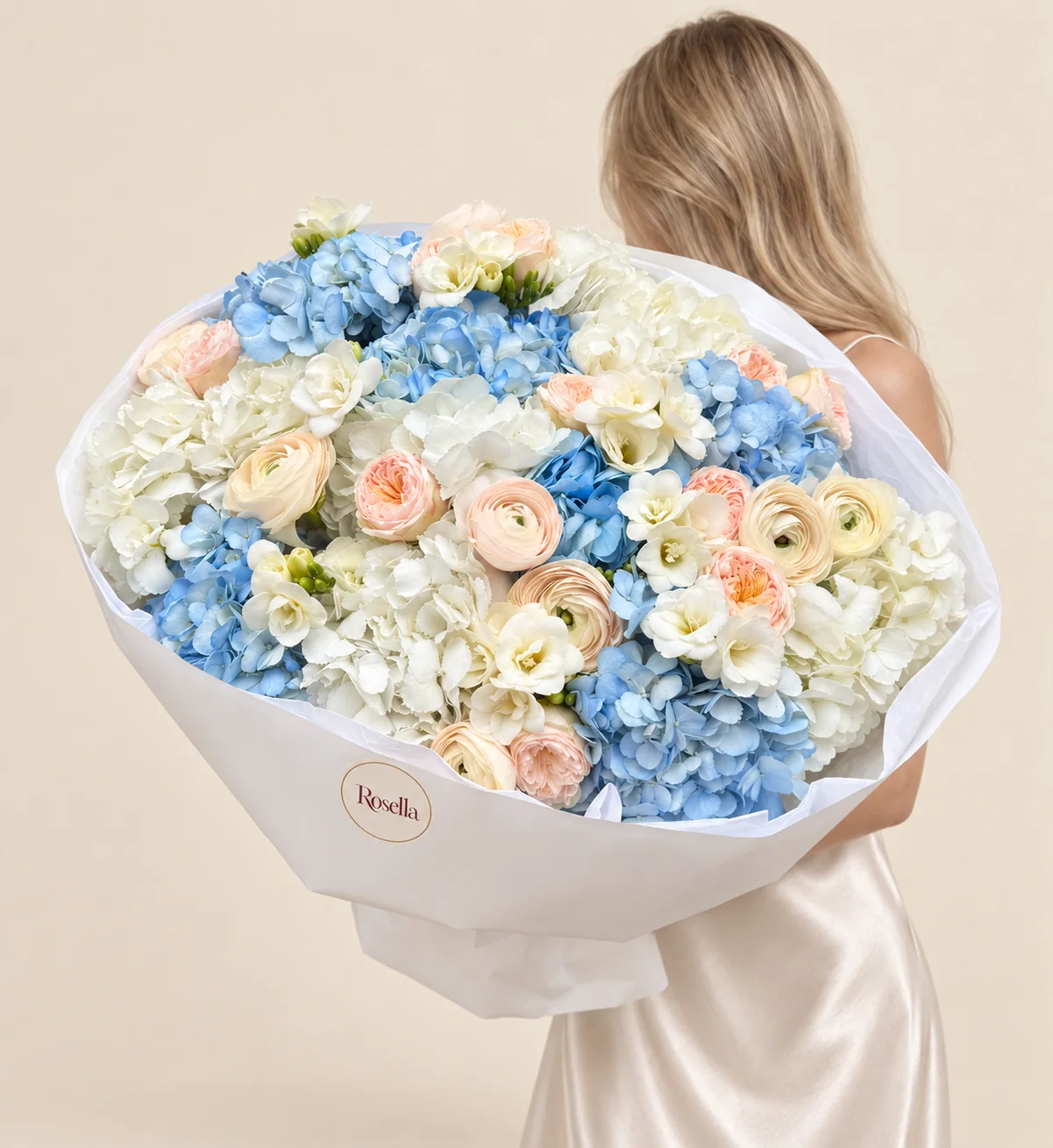 7 blue hydrangeas, 6 white hydrangeas, 12 garden roses, 6 cream ranunculus, 6 freesias & 1 blush ranunculus in a hand-tied bouquet