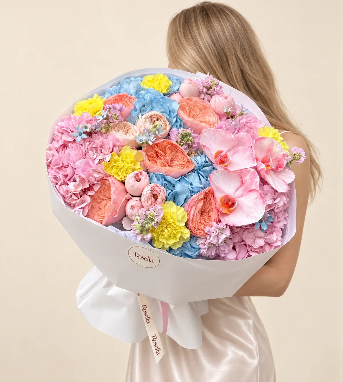 5 blue hydrangeas, 5 pink hydrangeas, 7 pink garden roses, 6 peach garden roses, 4 stocks, 7 carnations, 2 cream garden roses, 3 orchid blooms & 10 tweedia blooms in a hand-tied bouquet