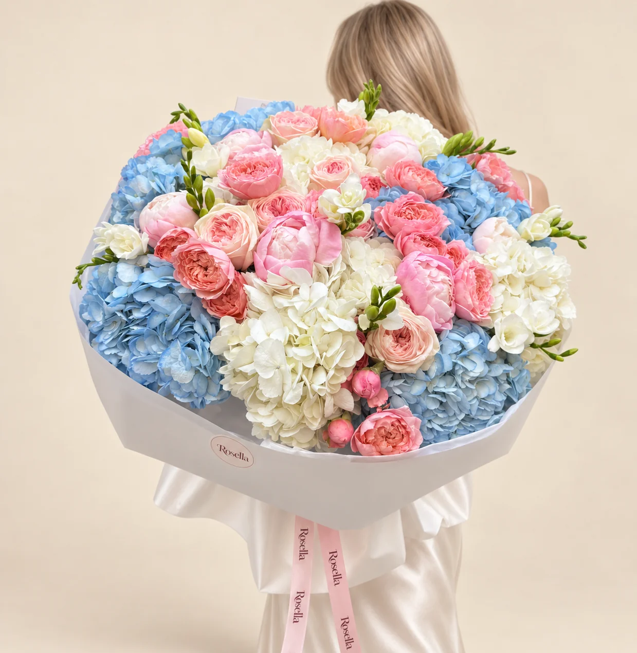 6 blue hydrangeas, 6 white hydrangeas, 7 peonies, 22 coral spray roses, 7 cream spray roses & 4 freesias in a hand-tied bouquet