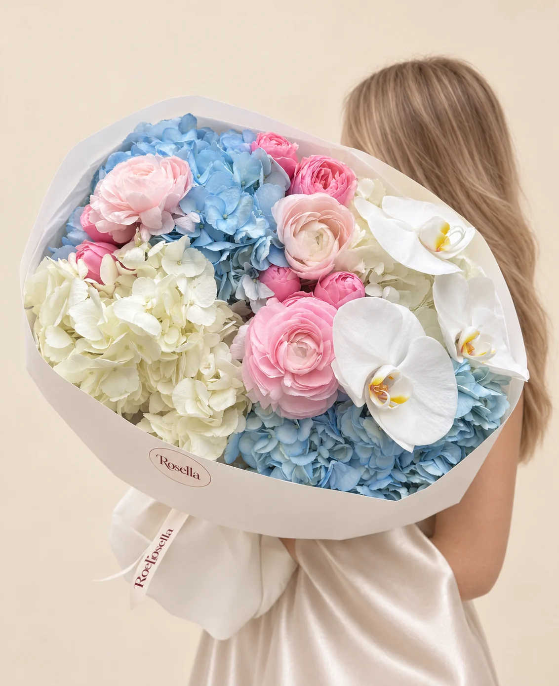 2 blue hydrangeas, 2 cream hydrangeas, 6 pink ranunculus, 4 pink ranunculus & 3 orchid blooms in a hand-tied bouquet