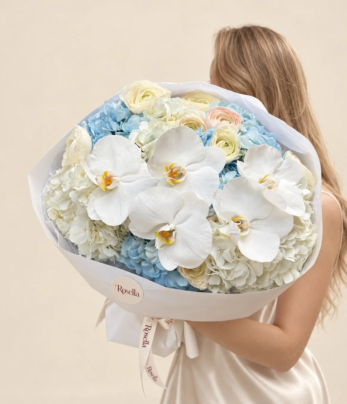 4 white hydrangeas, 3 blue hydrangeas, 8 white ranunculus, 5 orchid blooms & 1 blush ranunculus in a hand-tied bouquet