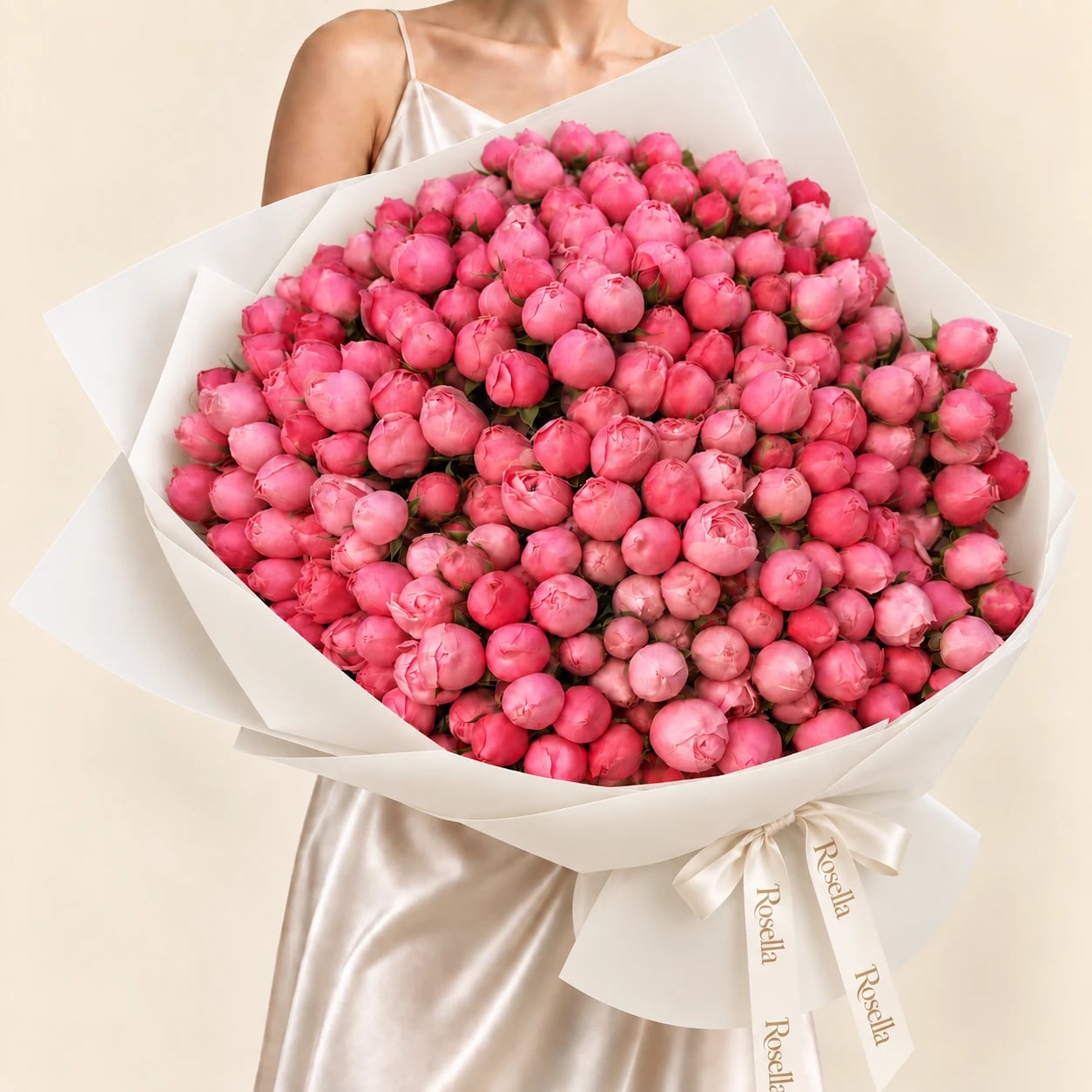 A huge dome of 165 pink peony buds in wide ivory wrap tied with a Rosella ribbon, held by a woman in a champagne satin dress